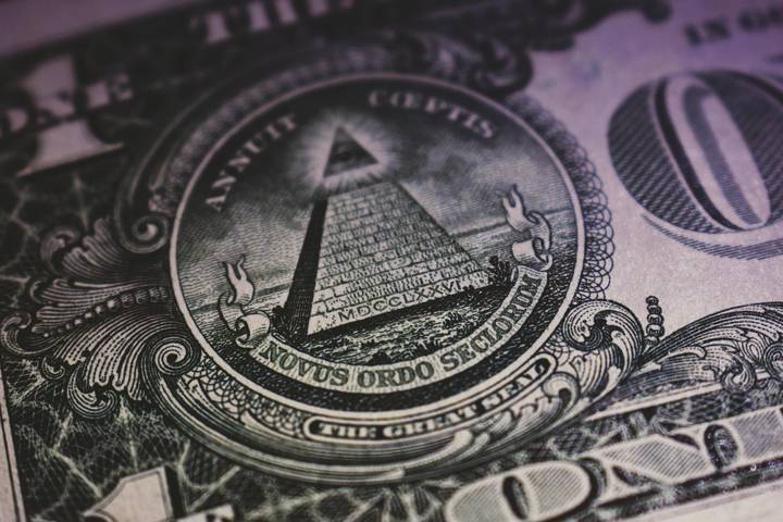 A close-up of the Great Seal on the back of a U.S. one-dollar bill, showing the pyramid with an eye at the top and the words 'Annuit Coeptis' and 'Novus Ordo Seclorum' in Latin, with detailed engraving patterns around the seal.