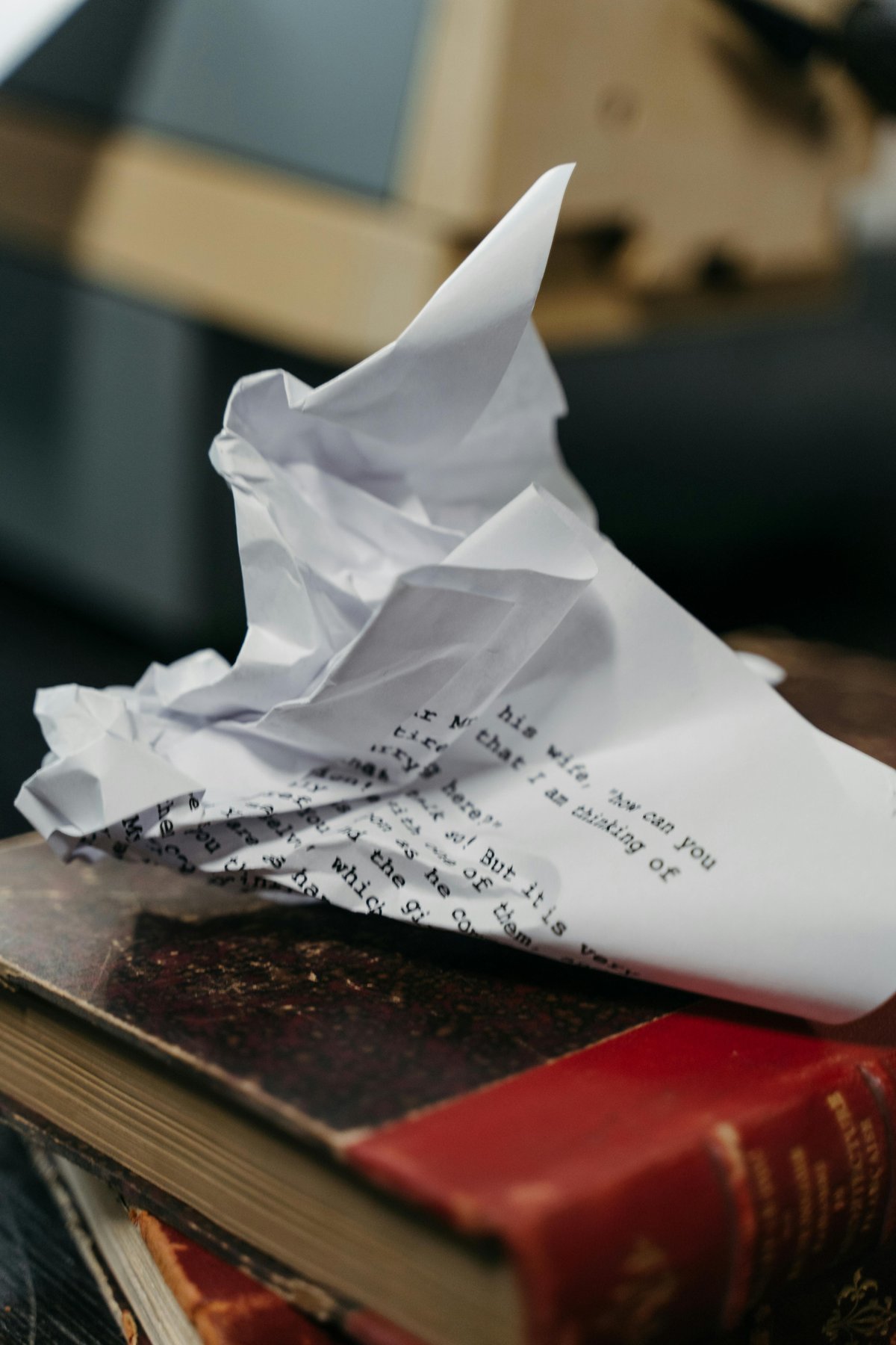 Crumpled paper sitting on top of stack of books.