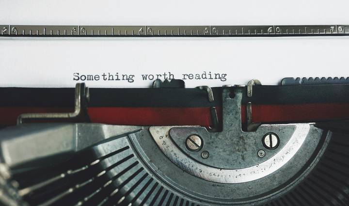 Close-up of a vintage typewriter with “Something worth reading” typed on the page.