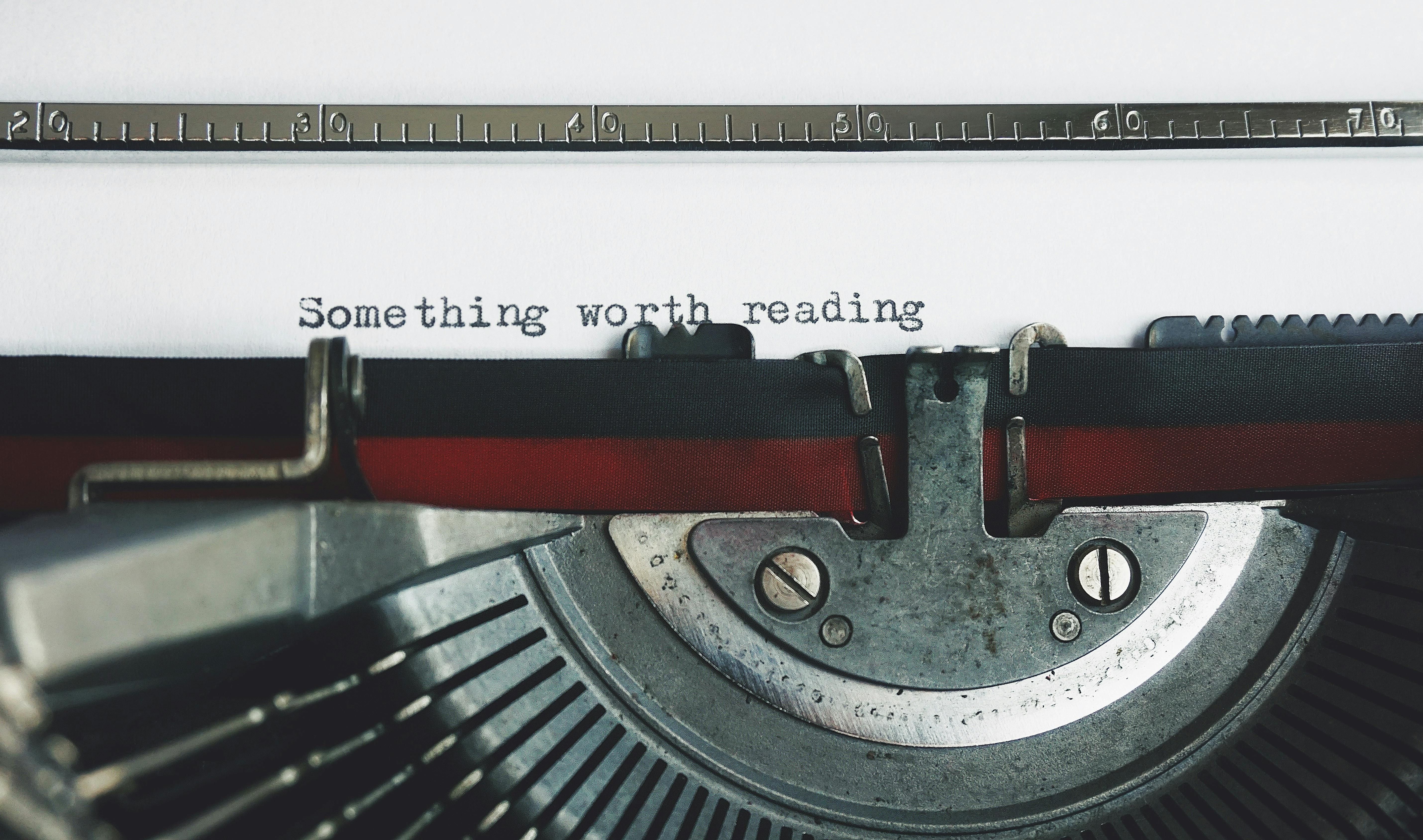 Close-up of a vintage typewriter with “Something worth reading” typed on the page.